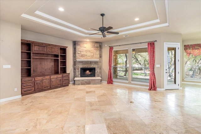 118 NE Verrena Way, Georgetown, TX 78628 - unfurnished living room featuring a tray ceiling, a fireplace, a ceiling fan, healthy amount of natural light, and ornamental molding