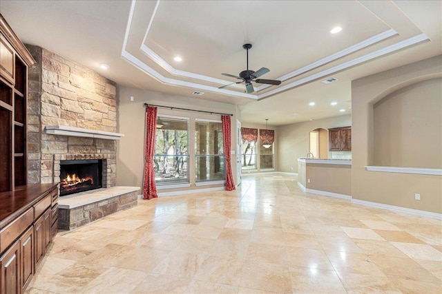 118 NE Verrena Way, Georgetown, TX 78628 - unfurnished living room with a tray ceiling, a stone fireplace, ceiling fan, recessed lighting, and crown molding