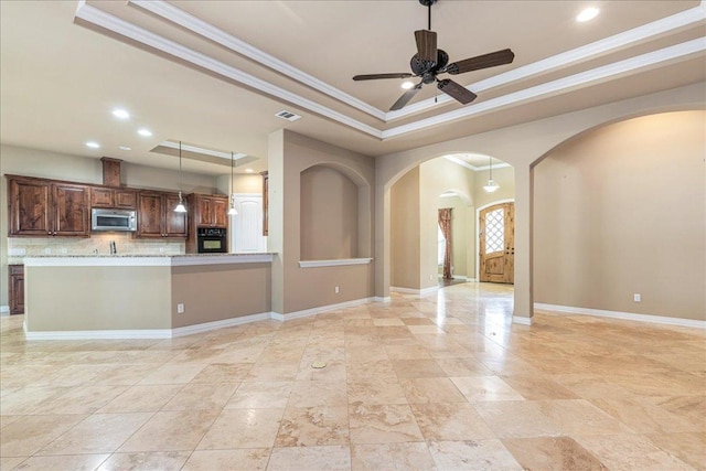 118 NE Verrena Way, Georgetown, TX 78628 - unfurnished living room with arched walkways, a raised ceiling, ornamental molding, ceiling fan, and baseboards