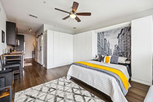3114 S Congress Ave Unit 304, Austin, TX 78704 - bedroom featuring dark wood-style flooring, a barn door, baseboards, and a ceiling fan