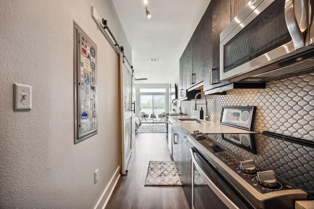 3114 S Congress Ave Unit 304, Austin, TX 78704 - kitchen with stainless steel microwave, range with electric cooktop, a barn door, a sink, and wood finished floors