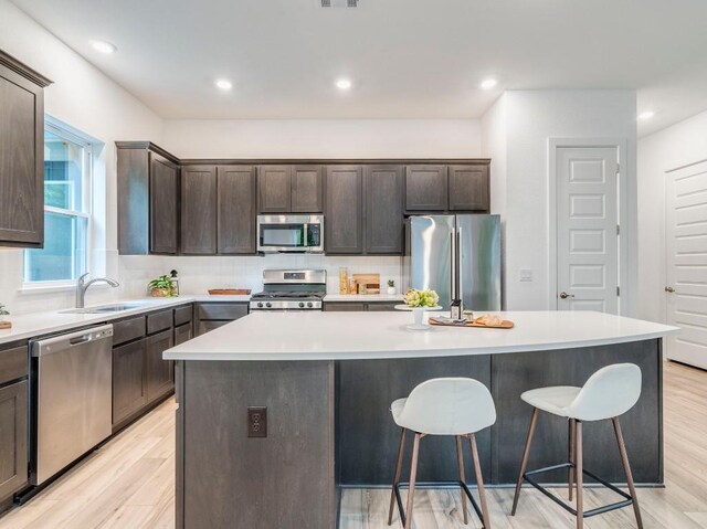 1108 Floradale Dr, Austin, TX 78753 - kitchen with appliances with stainless steel finishes, a sink, a center island, a breakfast bar, and dark brown cabinetry
