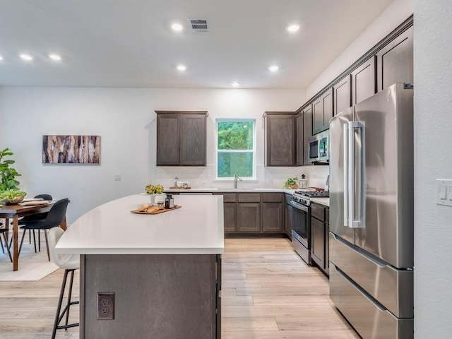 1108 Floradale Dr, Austin, TX 78753 - kitchen with stainless steel appliances, a center island, light wood-style flooring, dark brown cabinetry, and recessed lighting