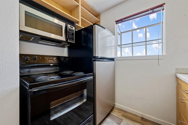 6903 Deatonhill Dr Unit 15, Austin, TX 78745 - kitchen with appliances with stainless steel finishes, baseboards, and light wood finished floors
