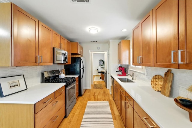 5202 Hedgewood Dr, Austin, TX 78745 - kitchen with stainless steel appliances, a sink, ornamental molding, light wood finished floors, and light countertops