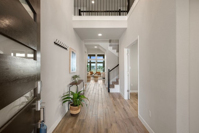4356 Mayfield Ranch Blvd, Round Rock, TX 78681 - hallway featuring baseboards, wood finished floors, stairs, and a towering ceiling