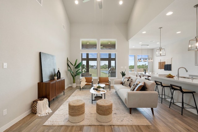 4356 Mayfield Ranch Blvd, Round Rock, TX 78681 - living room featuring light wood-style flooring, a chandelier, a towering ceiling, baseboards, and ceiling fan