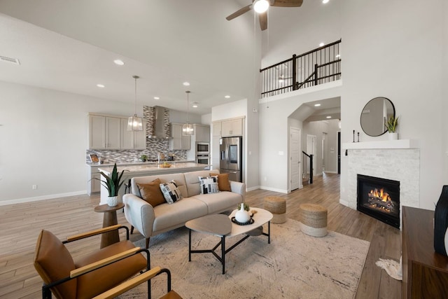 4356 Mayfield Ranch Blvd, Round Rock, TX 78681 - living room featuring baseboards, a ceiling fan, light wood-style floors, a glass covered fireplace, and recessed lighting