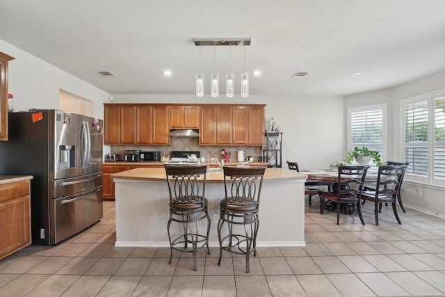 4013 Veiled Falls Dr, Pflugerville, TX 78660 - kitchen with stainless steel fridge, range with gas stovetop, under cabinet range hood, light countertops, and recessed lighting