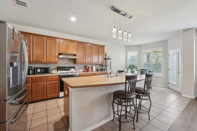 4013 Veiled Falls Dr, Pflugerville, TX 78660 - kitchen with stainless steel refrigerator with ice dispenser, range with gas cooktop, a sink, black microwave, and under cabinet range hood