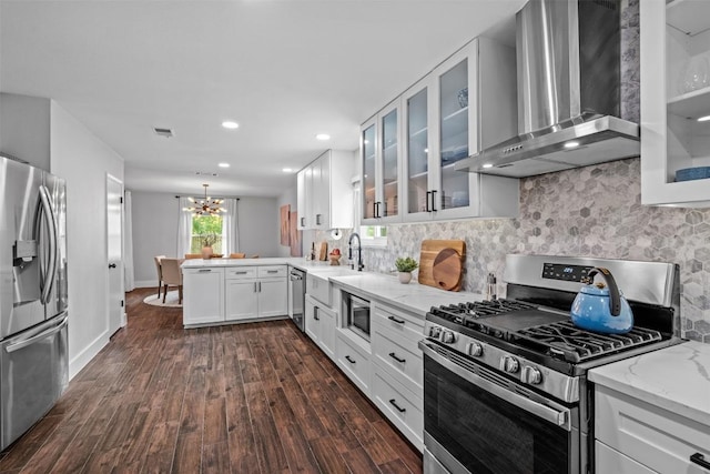 12420 Cassady Dr, Austin, TX 78727 - kitchen with appliances with stainless steel finishes, wall chimney range hood, dark wood-style flooring, a chandelier, and a peninsula