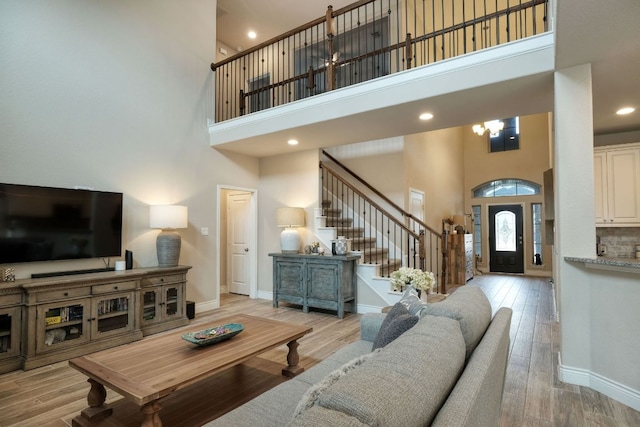 550 Cortona Ln, Georgetown, TX 78628 - living area featuring a high ceiling, stairs, baseboards, a chandelier, and light wood-type flooring