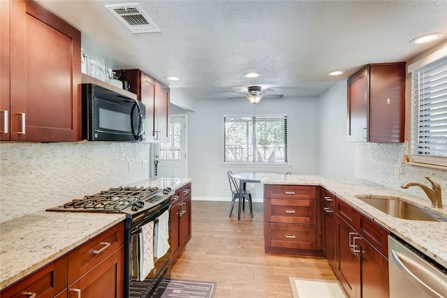 9214 Independence Loop, Austin, TX 78748 - kitchen with black appliances, light wood-style flooring, recessed lighting, plenty of natural light, and light stone counters