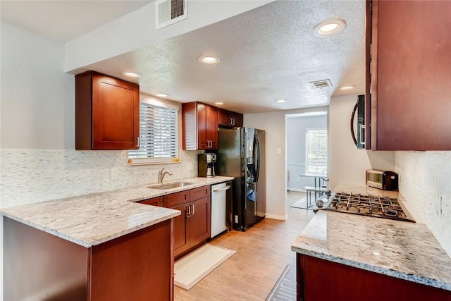 9214 Independence Loop, Austin, TX 78748 - kitchen with appliances with stainless steel finishes, decorative backsplash, a textured ceiling, light stone counters, and light wood finished floors