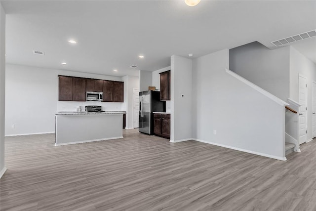 113 Bent Creek Ln, Georgetown, TX 78628 - kitchen with appliances with stainless steel finishes, open floor plan, light wood-style flooring, dark brown cabinets, and light countertops