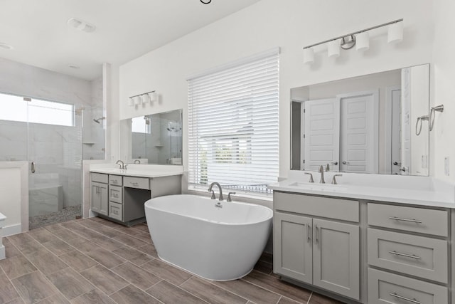 601 Gunison Dr, Lakeway, TX 78738 - full bath with a stall shower, two vanities, a freestanding bath, and wood tiled floors