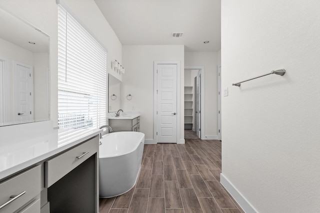 601 Gunison Dr, Lakeway, TX 78738 - full bath featuring two vanities, a closet, a freestanding tub, wood finished floors, and baseboards