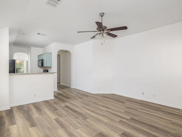 8425 Shallot Way, Austin, TX 78748 - unfurnished living room featuring arched walkways, a ceiling fan, wood finished floors, and baseboards