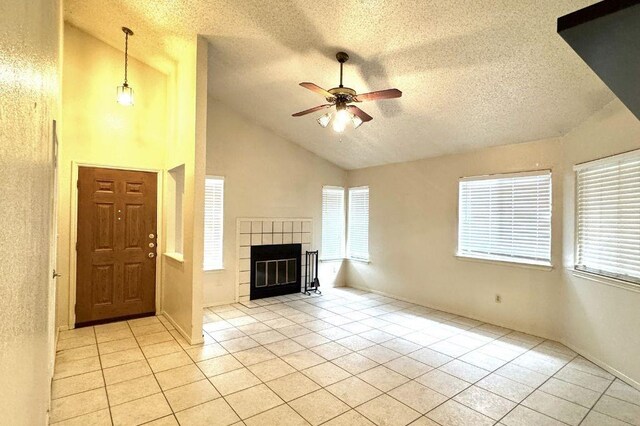 1121 Peggotty Pl, Austin, TX 78753 - unfurnished living room featuring a textured ceiling, ceiling fan, light tile patterned floors, a tiled fireplace, and high vaulted ceiling