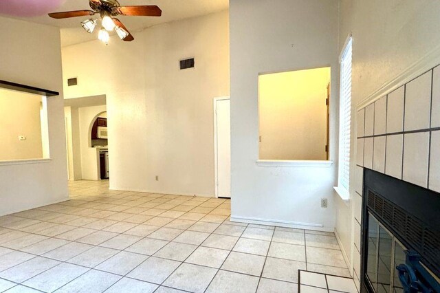 1121 Peggotty Pl, Austin, TX 78753 - unfurnished living room with a towering ceiling, a ceiling fan, arched walkways, a large fireplace, and light tile patterned floors