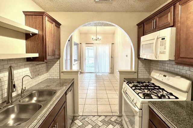 1121 Peggotty Pl, Austin, TX 78753 - kitchen featuring white appliances, arched walkways, a chandelier, tasteful backsplash, and a textured ceiling