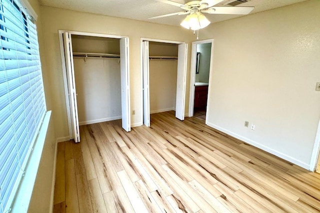 1121 Peggotty Pl, Austin, TX 78753 - unfurnished bedroom featuring two closets, light wood-style flooring, and ceiling fan