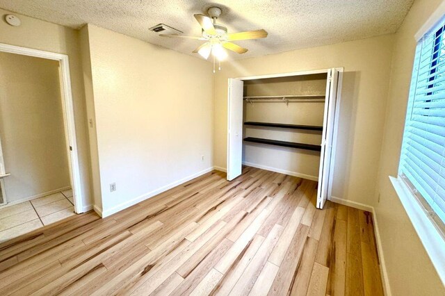 1121 Peggotty Pl, Austin, TX 78753 - unfurnished bedroom with a textured ceiling, a closet, light wood-type flooring, a ceiling fan, and multiple windows