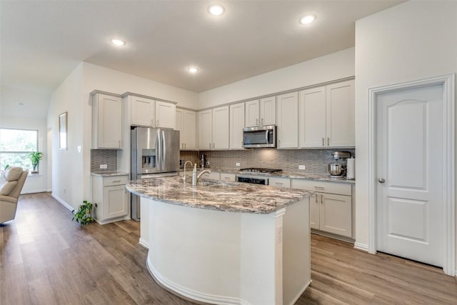 2212 Mcclendon Trl, Leander, TX 78641 - kitchen featuring stainless steel appliances, light wood-style flooring, backsplash, light stone counters, and a sink