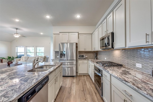 2212 Mcclendon Trl, Leander, TX 78641 - kitchen featuring appliances with stainless steel finishes, a sink, light wood-style floors, ceiling fan, and tasteful backsplash
