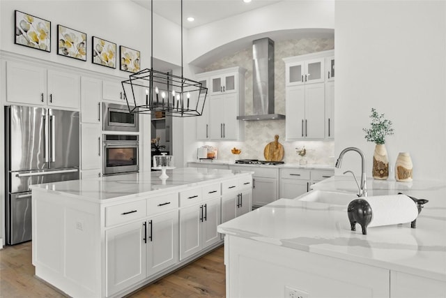 116 Egret Ln, Austin, TX 78737 - kitchen featuring stainless steel appliances, wall chimney exhaust hood, a sink, a center island, and arched walkways