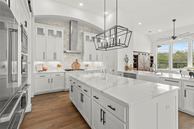 116 Egret Ln, Austin, TX 78737 - kitchen featuring wall chimney range hood, a kitchen island, stainless steel appliances, wood finished floors, and backsplash