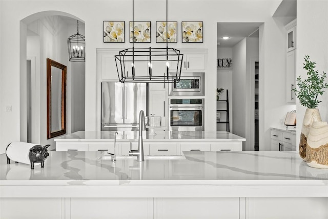 116 Egret Ln, Austin, TX 78737 - kitchen with stainless steel appliances, a chandelier, white cabinetry, decorative light fixtures, and arched walkways