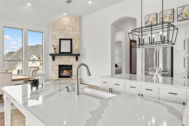 116 Egret Ln, Austin, TX 78737 - kitchen with stainless steel fridge, a sink, vaulted ceiling, arched walkways, and white cabinetry
