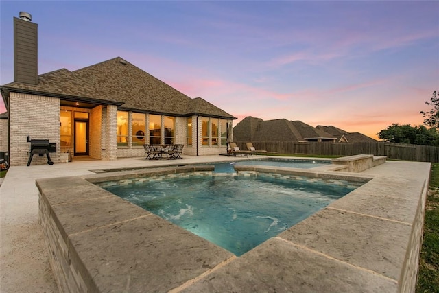 116 Egret Ln, Austin, TX 78737 - pool at dusk with a patio area, an in-ground hot tub, a fenced backyard, and area for grilling