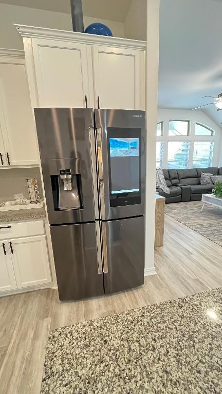 157 Monroe Dr, Kyle, TX 78640 - kitchen view of stainless steel refrigerator with ice dispenser, light wood-type flooring, white cabinetry, a ceiling fan, and light stone countertops