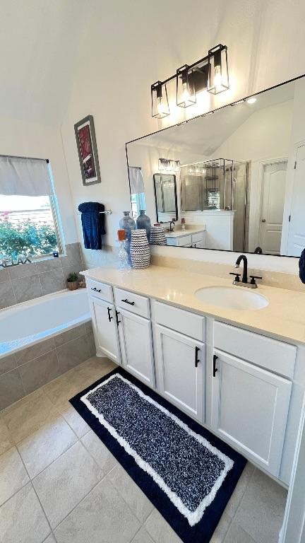 157 Monroe Dr, Kyle, TX 78640 - bathroom with vaulted ceiling, vanity, tile patterned flooring, and a bath