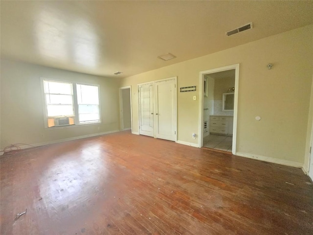 121 E Guadalupe St, La Grange, TX 78945 - unfurnished bedroom featuring wood finished floors, baseboards, cooling unit, and ensuite bath