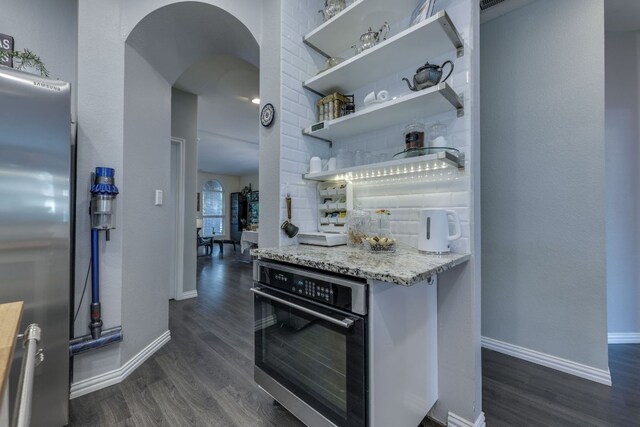 745 Bent Wood Pl, Round Rock, TX 78665 - kitchen with wall oven, stainless steel refrigerator, arched walkways, and dark wood finished floors