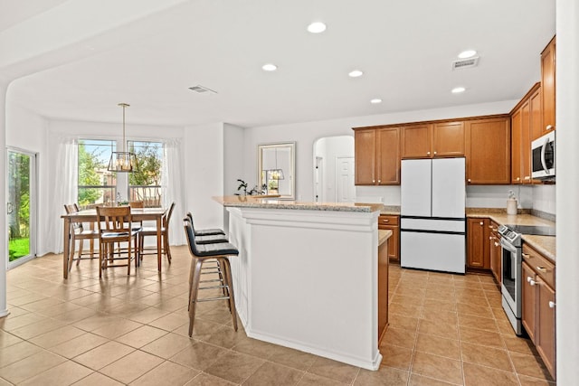 122 Mancos Dr, Georgetown, TX 78626 - kitchen with stainless steel appliances, brown cabinets, a kitchen island, recessed lighting, and light tile patterned floors