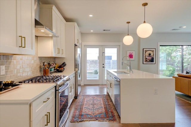 2504 Willow St Unit A, Austin, TX 78702 - kitchen featuring a sink, stainless steel appliances, wall chimney range hood, wood finished floors, and a center island with sink
