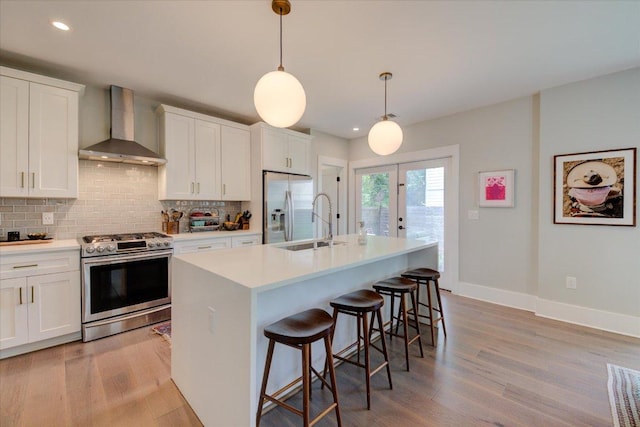 2504 Willow St Unit A, Austin, TX 78702 - kitchen with appliances with stainless steel finishes, wall chimney range hood, a sink, backsplash, and light wood-style floors