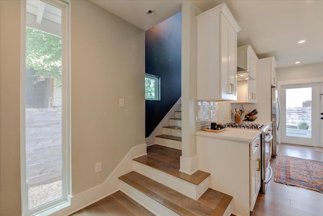 2504 Willow St Unit A, Austin, TX 78702 - kitchen featuring white cabinets, decorative backsplash, light countertops, light wood-type flooring, and freestanding refrigerator