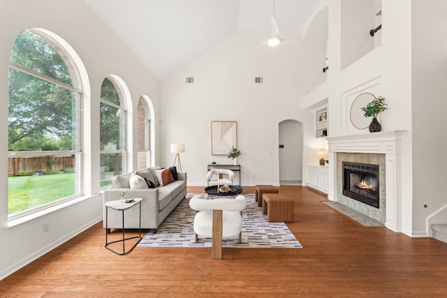 5708 Bexley Ct, Austin, TX 78739 - living area featuring a tiled fireplace, arched walkways, high vaulted ceiling, wood finished floors, and a ceiling fan