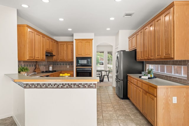 5708 Bexley Ct, Austin, TX 78739 - kitchen featuring black appliances, arched walkways, decorative backsplash, a peninsula, and recessed lighting