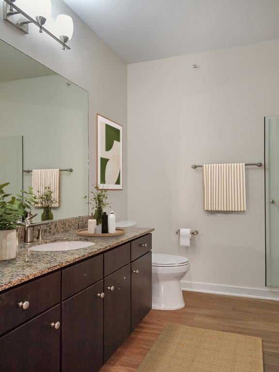 1900 Barton Springs Rd Unit 4013, Austin, TX 78704 - bathroom featuring wood finished floors, double vanity, toilet, and baseboards