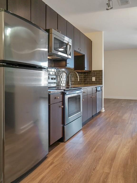 1900 Barton Springs Rd Unit 4013, Austin, TX 78704 - kitchen with appliances with stainless steel finishes, light wood finished floors, backsplash, and baseboards