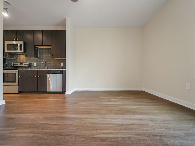 1900 Barton Springs Rd Unit 4013, Austin, TX 78704 - kitchen with appliances with stainless steel finishes, light wood finished floors, a sink, backsplash, and baseboards