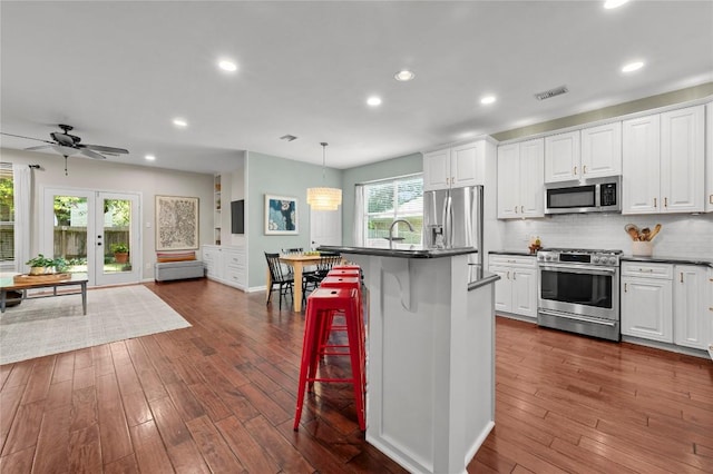 5929 Mesa Verde Cir, Austin, TX 78749 - kitchen featuring stainless steel appliances, dark countertops, white cabinetry, recessed lighting, and tasteful backsplash