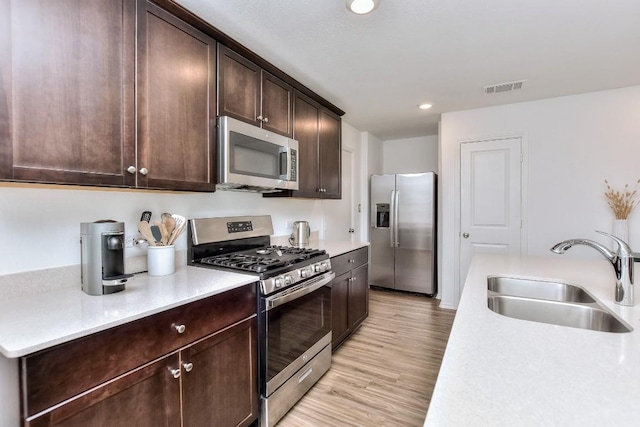159 Andross Ln, Bastrop, TX 78602 - kitchen featuring appliances with stainless steel finishes, a sink, dark brown cabinets, light countertops, and light wood-style floors