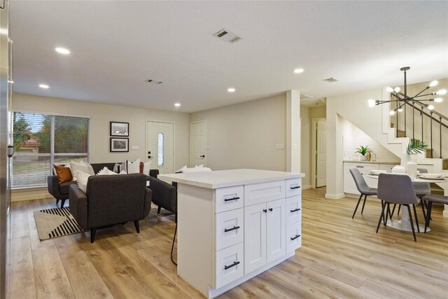 4507 Elana Ct, Austin, TX 78741 - kitchen with light wood finished floors, a chandelier, white cabinetry, a kitchen island, and light countertops